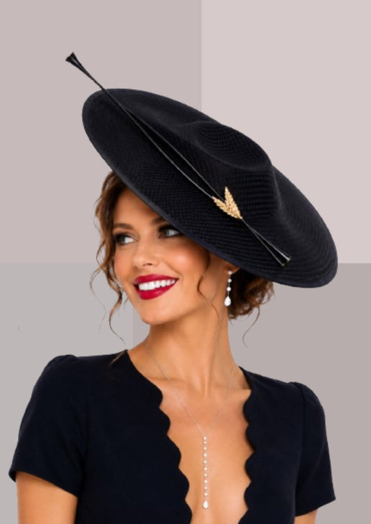 Grand chapeau noir de cérémonie porté sur le côté de la tête, orné d'une plume graphique et d'un détail doré. Création élégante pour mariage ou réception. | Cap-Chapeau