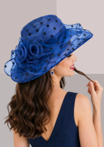 femme de dos robe bleue , capeline à pois bleu saphir, elle porte également des saphirs aux oreilles et tortille entre ses doigts une mèche de cheveux qu'elle a chatains foncés | Cap-Chapeau
