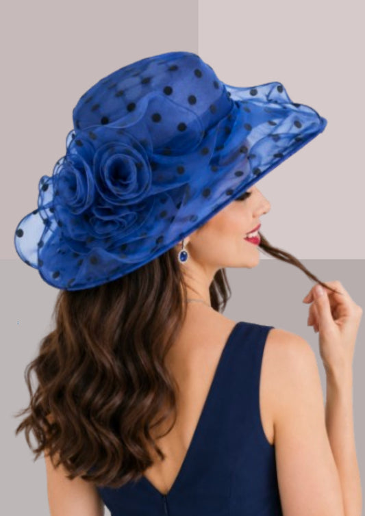 femme de dos robe bleue , capeline à pois bleu saphir, elle porte également des saphirs aux oreilles et tortille entre ses doigts une mèche de cheveux qu'elle a chatains foncés | Cap-Chapeau