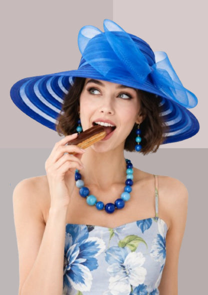 Femme brune, mangeant un éclair au chocolat, en tenue de réception: robe bleue à fleurs et capeline bleu France | Cap-Chapeau